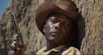 Movie still from “Buck and the Preacher” (1972), directed by Joseph Sargent – A man wearing a cowboy hat leaning against a wall; Close Up shot, Low angle