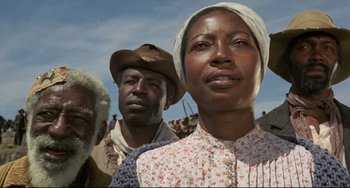 Movie still from “Buck and the Preacher” (1972), directed by Joseph Sargent – A group of people standing next to each other on a field; Close Up shot, Low angle
