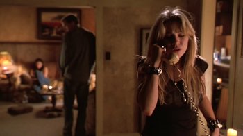 Movie still from “Bug” (2006), directed by William Friedkin – A woman talking on a phone while standing next to a man; Medium shot, Low angle