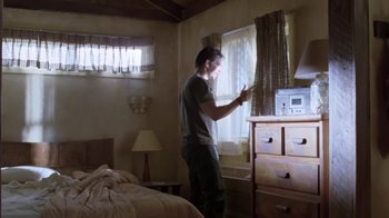 Movie still from “Bug” (2006), directed by William Friedkin – A man standing in front of a window in a room; Wide shot, Low angle
