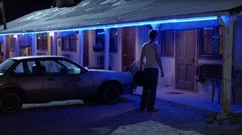 Movie still from “Bug” (2006), directed by William Friedkin – A man standing in front of a car in a parking lot at night; Wide shot, Over the shoulder angle