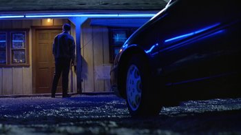 Movie still from “Bug” (2006), directed by William Friedkin – A man standing in front of a car at night; Wide shot, Low angle