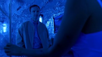 Movie still from “Bug” (2006), directed by William Friedkin – A man standing in front of a woman in a blue room; Medium shot, Over the shoulder angle