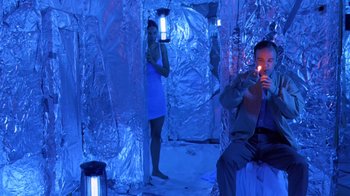 Movie still from “Bug” (2006), directed by William Friedkin – A man and a woman are in a room with lights; Medium shot, High angle