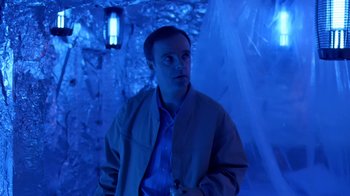 Movie still from “Bug” (2006), directed by William Friedkin – A man standing in a room lit by a blue light; Medium shot, Low angle