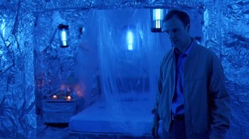 Movie still from “Bug” (2006), directed by William Friedkin – A man standing next to a bed in a room; Medium shot, Low angle