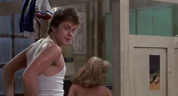 Movie still from “Bull Durham” (1988), directed by Ron Shelton – A man in a white tank top is looking at a woman in a white tank top; Medium shot, Over the shoulder angle