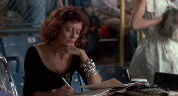 Movie still from “Bull Durham” (1988), directed by Ron Shelton – A woman sitting at a table writing on a piece of paper; Close Up shot, Over the shoulder angle