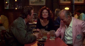 Movie still from “Bull Durham” (1988), directed by Ron Shelton – A group of people sitting at a table with drinks; Medium shot, Over the shoulder angle