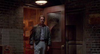 Movie still from “Bull Durham” (1988), directed by Ron Shelton – A man standing in front of an open door; Medium shot, Low angle