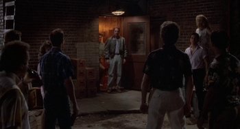 Movie still from “Bull Durham” (1988), directed by Ron Shelton – A group of people standing in a room; Wide shot, Over the shoulder angle