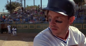 Movie still from “Bull Durham” (1988), directed by Ron Shelton – A baseball player with a hat and eye shadow on; Close Up shot, Over the shoulder angle