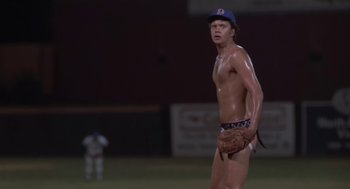 Movie still from “Bull Durham” (1988), directed by Ron Shelton – A shirtless baseball player holding a catchers mitts; Medium shot, Low angle