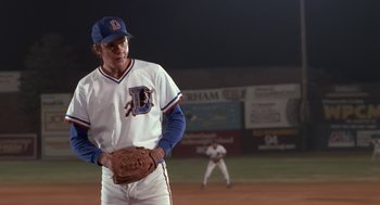Movie still from “Bull Durham” (1988), directed by Ron Shelton – A baseball player is standing on a field; Medium shot, Over the shoulder angle