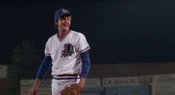 Movie still from “Bull Durham” (1988), directed by Ron Shelton – A baseball player is smiling while standing on a field; Medium shot, Low angle