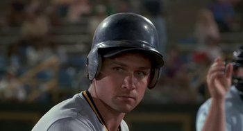 Movie still from “Bull Durham” (1988), directed by Ron Shelton – A baseball player wearing a black helmet and a white uniform; Close Up shot, Over the shoulder angle