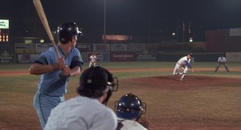 Movie still from “Bull Durham” (1988), directed by Ron Shelton – A baseball player swinging a bat at a baseball game; Wide shot, Over the shoulder angle