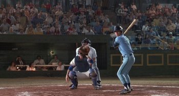Movie still from “Bull Durham” (1988), directed by Ron Shelton – A baseball player holding a bat on a field; Wide shot, Over the shoulder angle