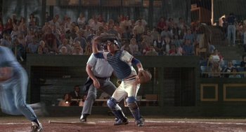 Movie still from “Bull Durham” (1988), directed by Ron Shelton – A baseball player swinging a bat at a ball; Wide shot, Over the shoulder angle