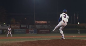 Movie still from “Bull Durham” (1988), directed by Ron Shelton – A baseball player is throwing a ball on a field; Wide shot, Low angle