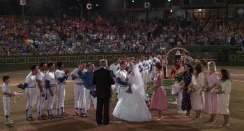 Movie still from “Bull Durham” (1988), directed by Ron Shelton – A bride and a groom are standing in front of a group of people; Wide shot, High angle
