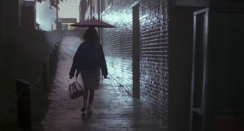 Movie still from “Bull Durham” (1988), directed by Ron Shelton – A woman walking down a street holding an umbrella; Wide shot, Low angle
