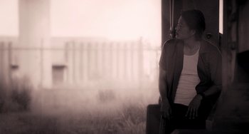 Movie still from “Bullet to the Head” (2012), directed by Walter Hill – A woman sitting on a bench next to a suitcase; Medium shot, Low angle