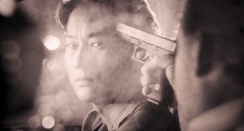 Movie still from “Bullet to the Head” (2012), directed by Walter Hill – A black and white photo of a man holding a gun; Extreme Close Up shot, Over the shoulder angle