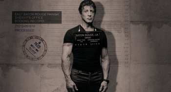 Movie still from “Bullet to the Head” (2012), directed by Walter Hill – A man in a black shirt is standing in front of a brick wall; Medium shot, Low angle