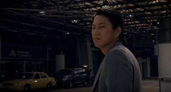Movie still from “Bullet to the Head” (2012), directed by Walter Hill – A man standing in a parking lot next to cars; Close Up shot, Low angle