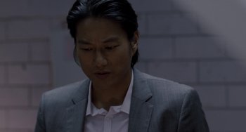 Movie still from “Bullet to the Head” (2012), directed by Walter Hill – A man wearing a suit and tie looking down; Close Up shot, Over the shoulder angle