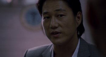 Movie still from “Bullet to the Head” (2012), directed by Walter Hill – A person wearing a suit; Close Up shot, Over the shoulder angle