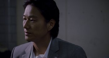 Movie still from “Bullet to the Head” (2012), directed by Walter Hill – A person wearing a suit and tie; Close Up shot, Over the shoulder angle