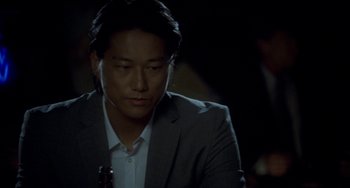Movie still from “Bullet to the Head” (2012), directed by Walter Hill – A man in a gray suit is listening to music; Close Up shot, Over the shoulder angle