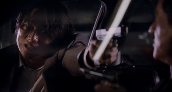 Movie still from “Bullet to the Head” (2012), directed by Walter Hill – A person holding a gun in a dark room; Close Up shot, Over the shoulder angle