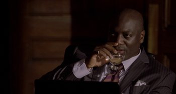 Movie still from “Bullet to the Head” (2012), directed by Walter Hill – A man in a suit and tie drinking a glass of wine; Close Up shot, High angle