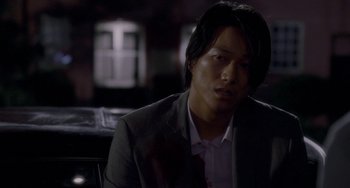Movie still from “Bullet to the Head” (2012), directed by Walter Hill – A man wearing a suit and tie sitting in front of a window; Close Up shot, Over the shoulder angle