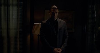 Movie still from “Bullet to the Head” (2012), directed by Walter Hill – A man standing in a dimly - lit dark room; Medium shot, Low angle