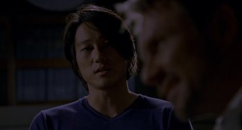 Movie still from “Bullet to the Head” (2012), directed by Walter Hill – A man with long black hair is looking at the camera; Close Up shot, Over the shoulder angle