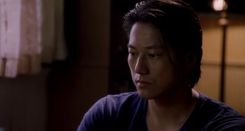 Movie still from “Bullet to the Head” (2012), directed by Walter Hill – A man with long hair sitting in a room; Close Up shot, Over the shoulder angle