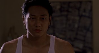 Movie still from “Bullet to the Head” (2012), directed by Walter Hill – A young man in a white tank top looking at the camera; Close Up shot, Over the shoulder angle