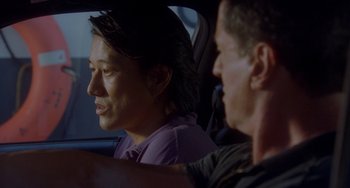 Movie still from “Bullet to the Head” (2012), directed by Walter Hill – A man and a woman sitting in the back of a car; Close Up shot, Over the shoulder angle