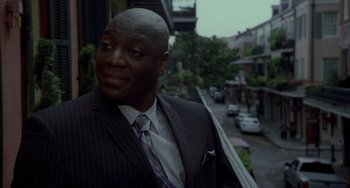 Movie still from “Bullet to the Head” (2012), directed by Walter Hill – A man wearing a suit and tie standing next to a street; Close Up shot, Over the shoulder angle