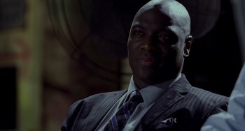 Movie still from “Bullet to the Head” (2012), directed by Walter Hill – A man wearing a suit and tie in front of a wall; Close Up shot, Low angle