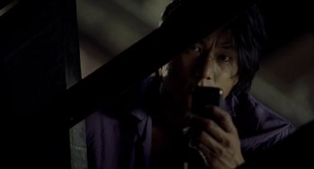 Movie still from “Bullet to the Head” (2012), directed by Walter Hill – A man holding a cell phone while standing next to a window; Close Up shot, High angle