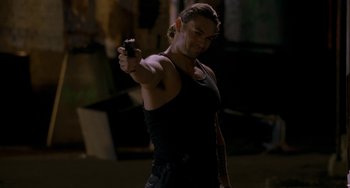 Movie still from “Bullet to the Head” (2012), directed by Walter Hill – A man holding a gun while standing in the dark; Medium shot, Over the shoulder angle