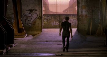 Movie still from “Bullet to the Head” (2012), directed by Walter Hill – A man walking down a street holding a skateboard; Wide shot, Low angle