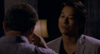 Movie still from “Bullet to the Head” (2012), directed by Walter Hill – A man is talking to another man in front of a lamp; Close Up shot, Over the shoulder angle