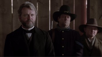 A man in a suit standing next to another man in a hat