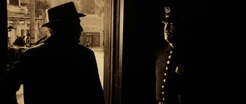 Movie still from “Butch Cassidy and the Sundance Kid” (1969), directed by George Roy Hill – A man in a uniform standing next to a door; Medium shot, Over the shoulder angle